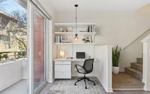 a view of a workspace with furniture and a window
