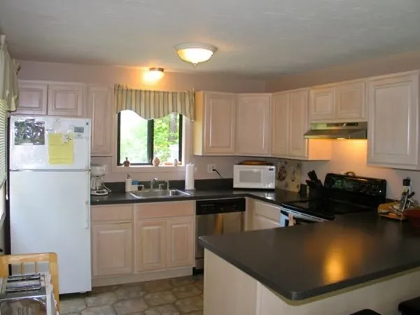 a kitchen with kitchen island granite countertop a sink a stove top oven a counter space and cabinets