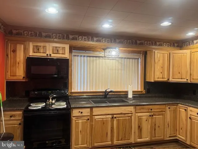 a kitchen with stainless steel appliances granite countertop a refrigerator a sink and white cabinets with wooden floor