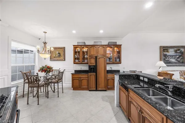 a kitchen with stainless steel appliances granite countertop a stove top oven a sink a dining table and chairs with wooden floor