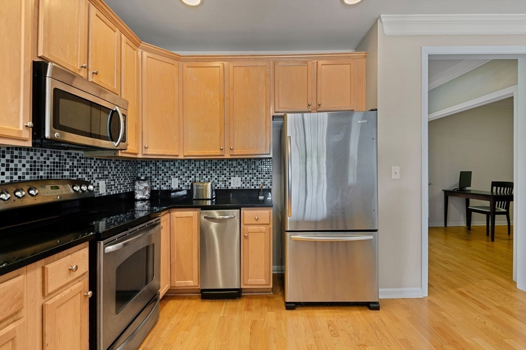 204 Clocktower Drive, Unit 202 Waltham, MA 02452 - Photo 11 of 25 a kitchen with stainless steel appliances granite countertop a refrigerator a stove a sink and a microwave
