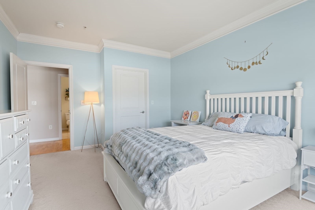 204 Clocktower Drive, Unit 202 Waltham, MA 02452 - Photo 15 of 25 a bedroom with a bed and wooden floor