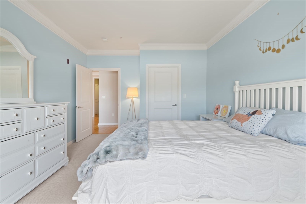 204 Clocktower Drive, Unit 202 Waltham, MA 02452 - Photo 17 of 25 a bedroom with a bed and a mirror