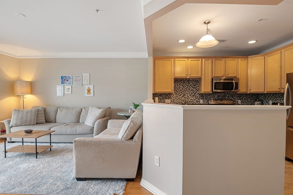 204 Clocktower Drive, Unit 202 Waltham, MA 02452 - Photo 5 of 25 a living room with furniture and a chandelier