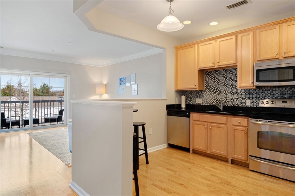 204 Clocktower Drive, Unit 202 Waltham, MA 02452 - Photo 6 of 25 a kitchen with granite countertop a stove a sink and a microwave