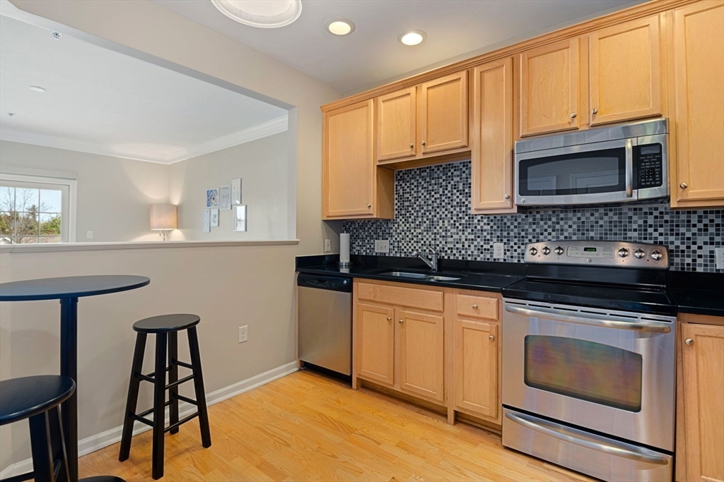 204 Clocktower Drive, Unit 202 Waltham, MA 02452 - Photo 8 of 25 a kitchen with stainless steel appliances granite countertop a stove a sink and a microwave