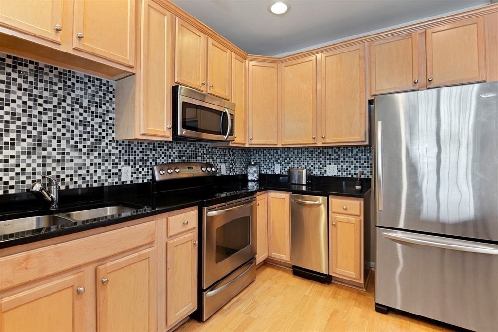 204 Clocktower Drive, Unit 202 Waltham, MA 02452 - Photo 9 of 25 a kitchen with granite countertop white cabinets and stainless steel appliances