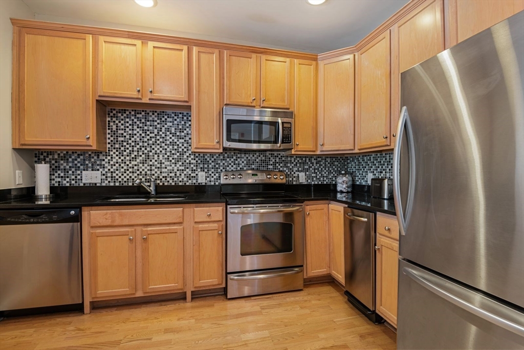 204 Clocktower Drive, Unit 202 Waltham, MA 02452 - Photo 10 of 25 a kitchen with granite countertop a refrigerator stove and sink