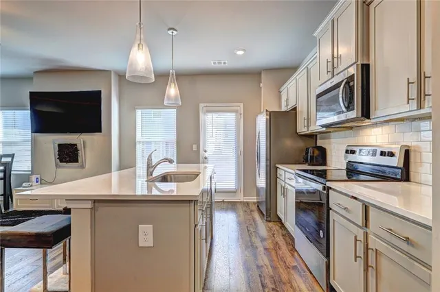 a kitchen with stainless steel appliances granite countertop a refrigerator a stove top oven a sink dishwasher and wooden cabinets with wooden floor