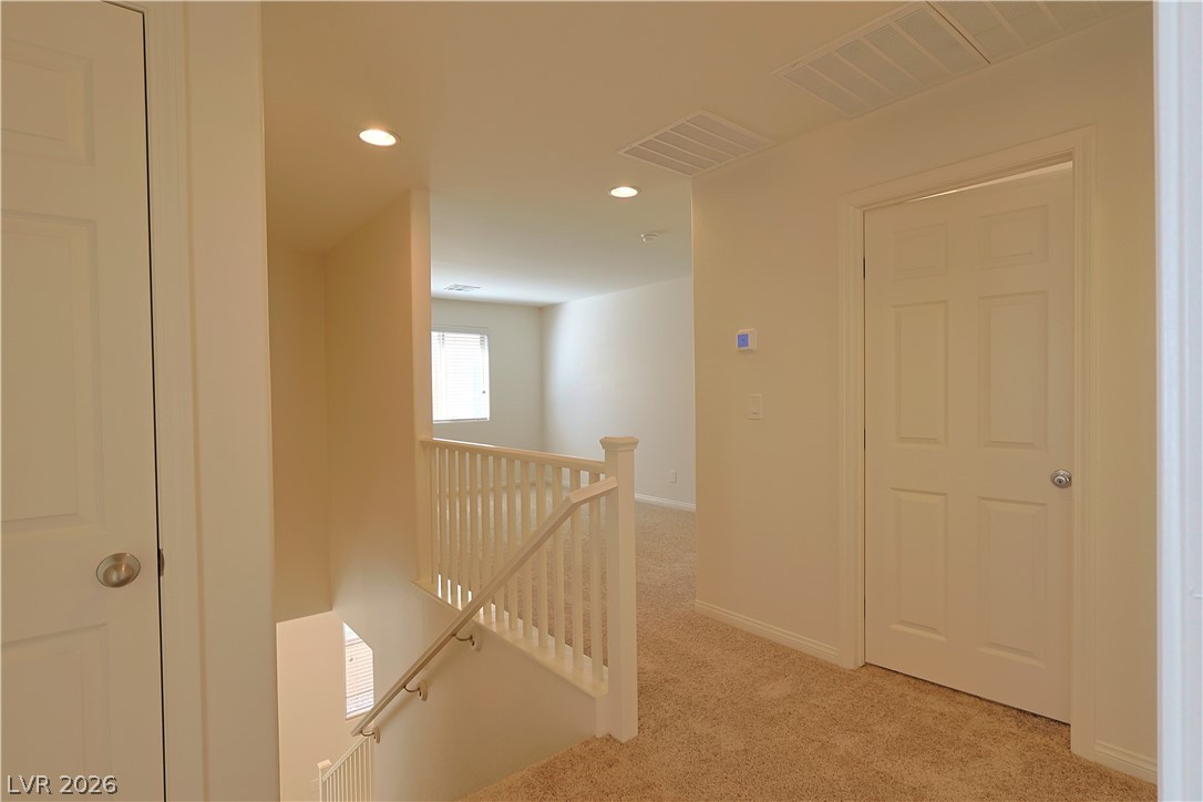8663 Reynolds Spring Street Las Vegas, NV 89178 - Photo 17 of 32 An upper-level hallway features warm carpeting and clean-lined drywall railings overlooking the staircase.