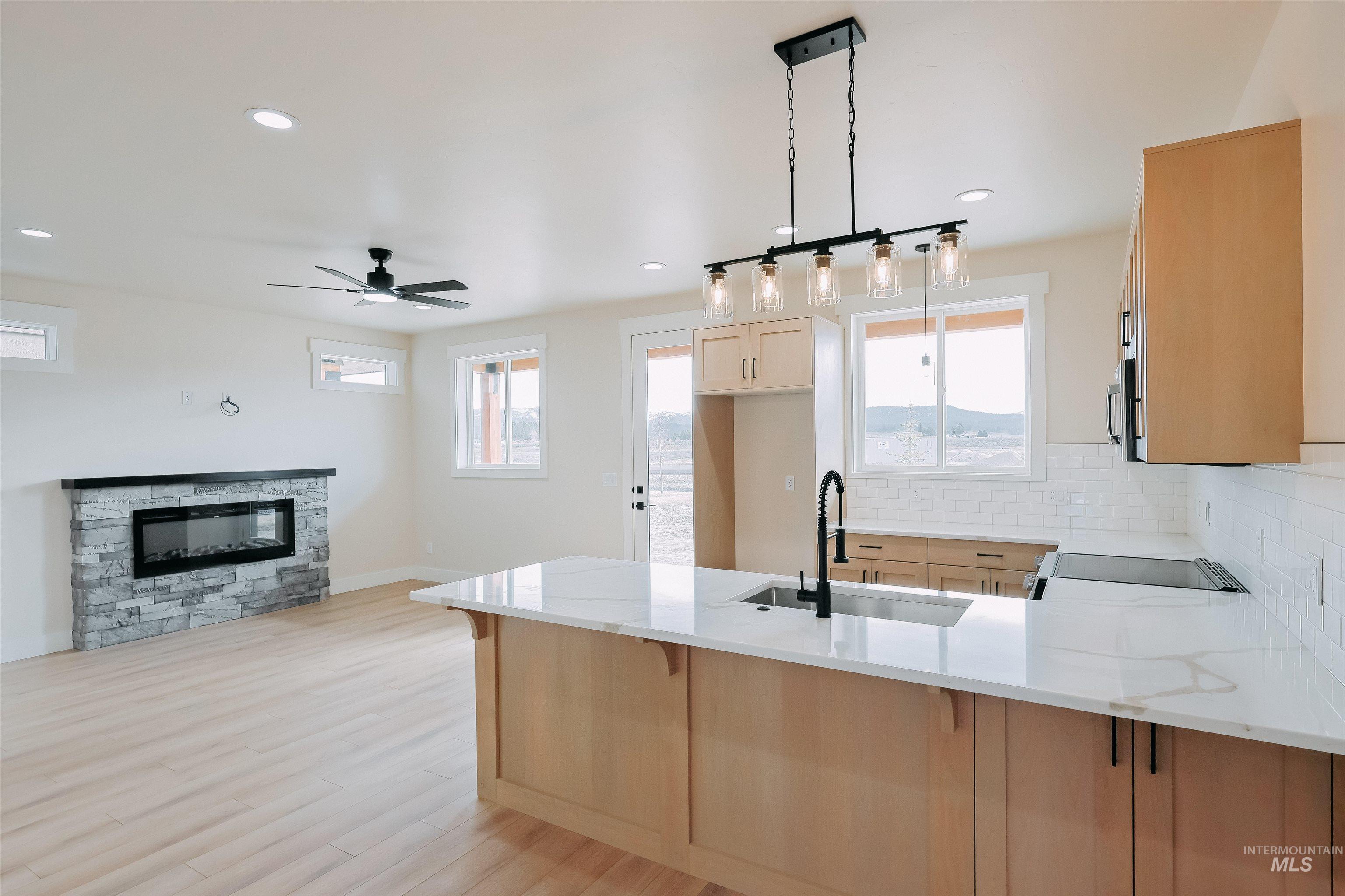 10 North Crk Way Cascade, ID 83611 - Photo 16 of 24 Kitchen featuring a peninsula, light stone countertops, light wood finish cabinetry, and decorative backsplash