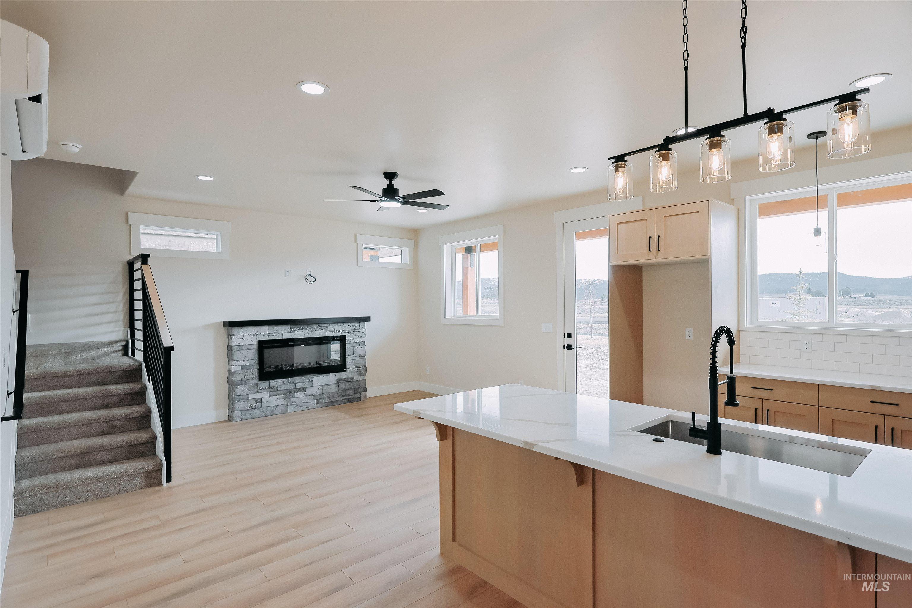 10 North Crk Way Cascade, ID 83611 - Photo 24 of 24 Kitchen with light wood finish cabinetry, a stone fireplace, open floor plan, light wood-type flooring, and light stone countertops