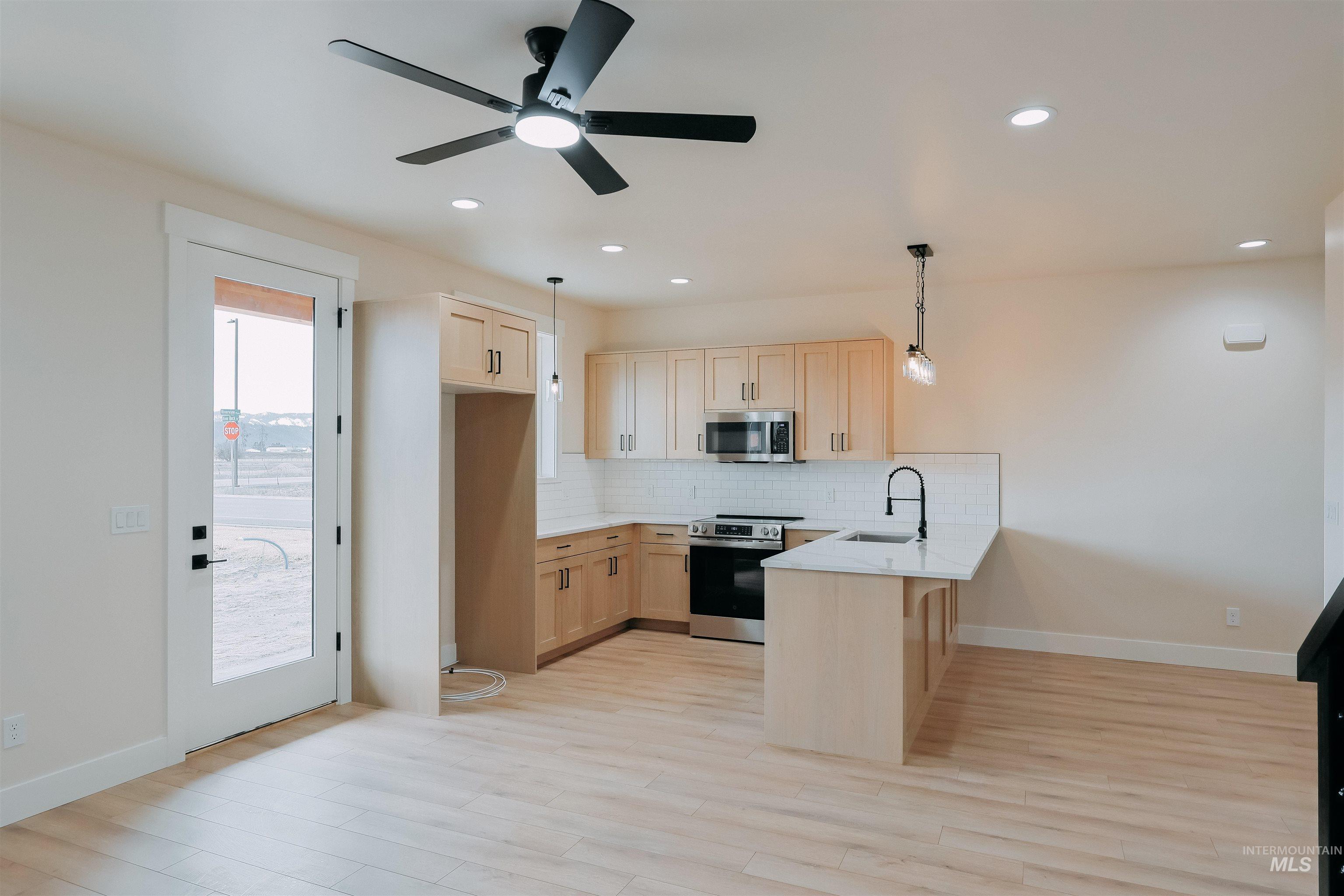 10 North Crk Way Cascade, ID 83611 - Photo 4 of 24 Kitchen featuring light wood finish cabinets, a peninsula, a kitchen breakfast bar, stainless steel appliances, and backsplash