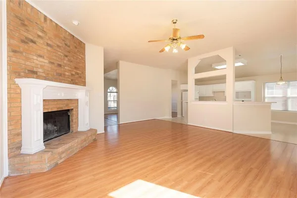 a view of an empty room with wooden floor and a fireplace