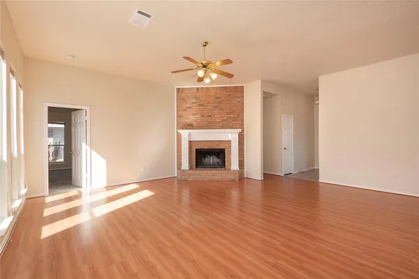 a view of an empty room with wooden floor fireplace and a window