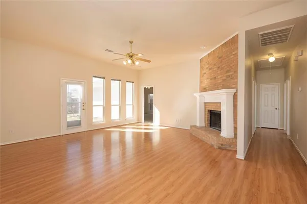 a view of an empty room with window and wooden floor