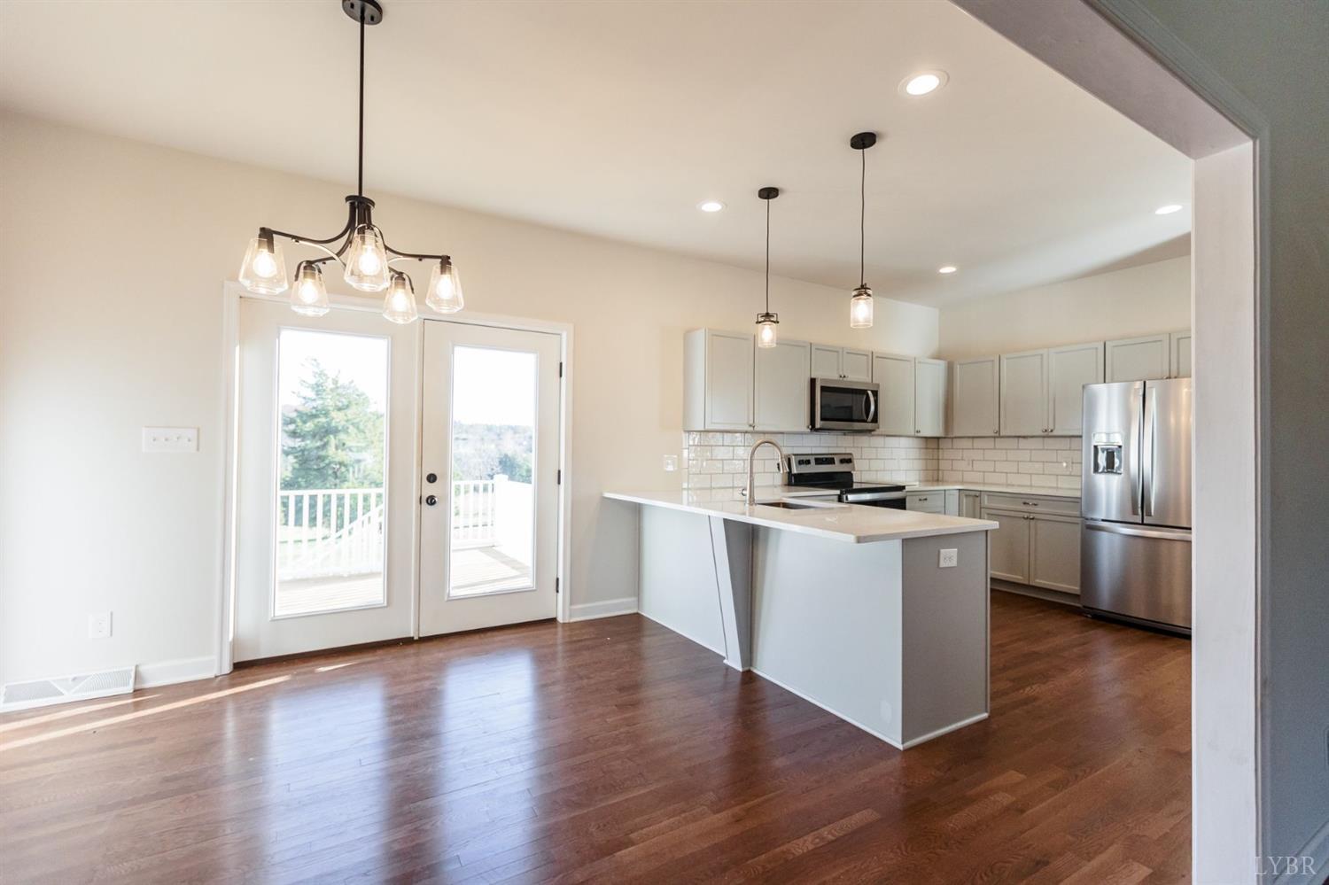 245 Country Estates Road Appomattox, VA 24522 - Photo 14 of 41 a large kitchen with white cabinets stainless steel appliances a center island and a chandelier