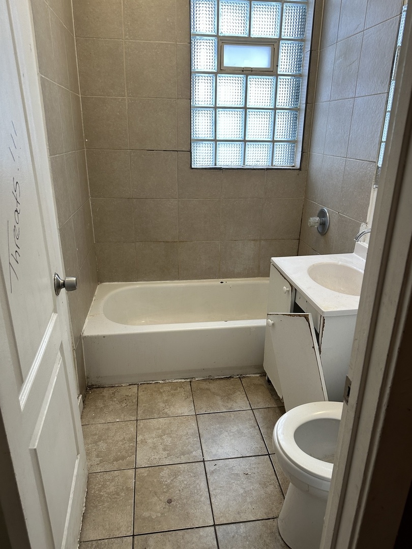 7216 South Green Street Chicago, IL 60621 - Photo 4 of 19 a bathroom with a sink a toilet and bathtub