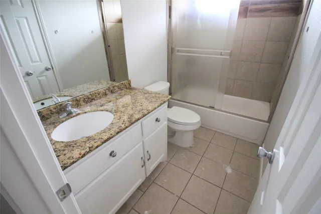 a bathroom with a granite countertop toilet and a sink