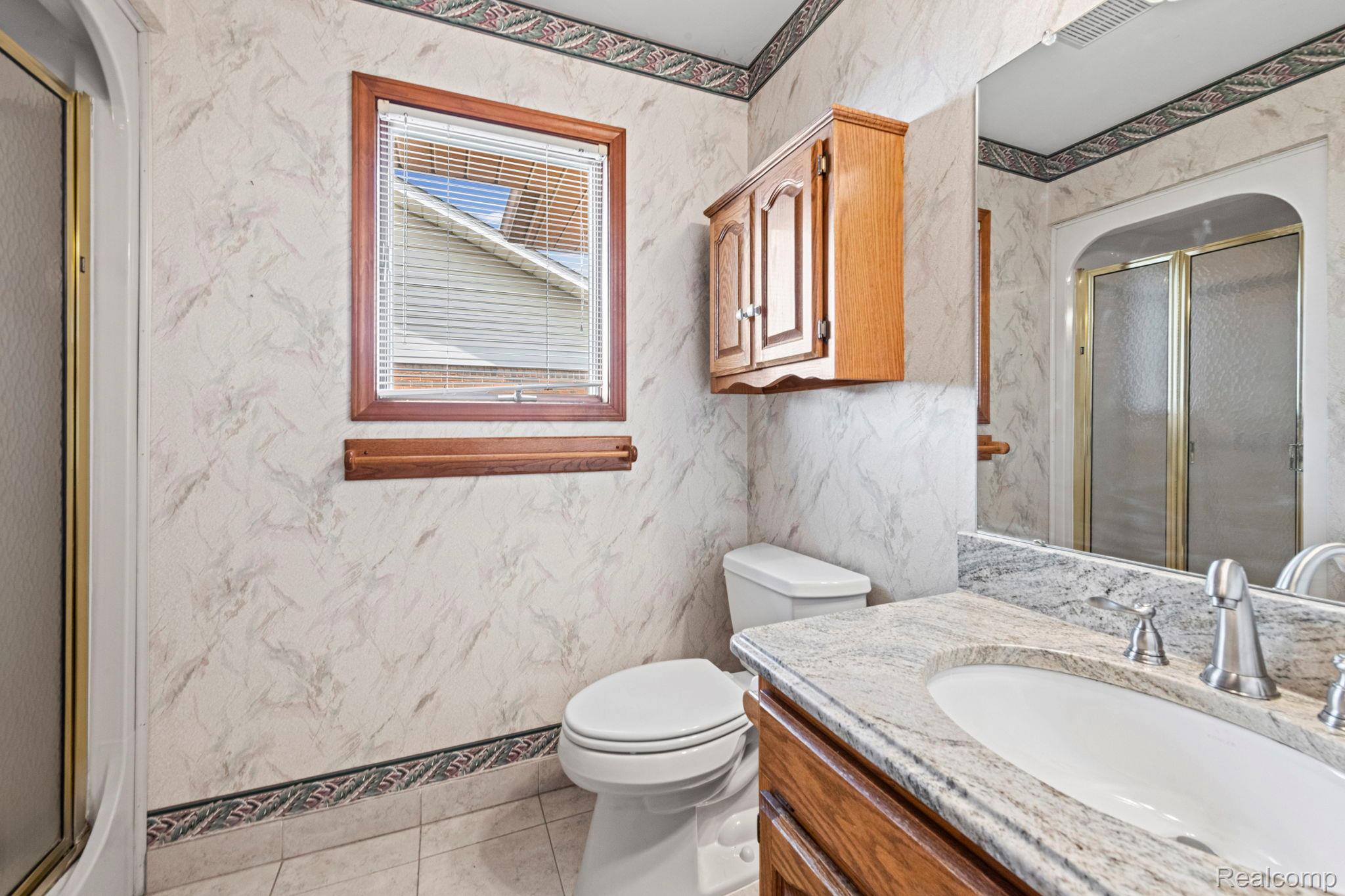 21580 Georgetown Road Trenton, MI 48183 - Photo 23 of 36 Bathroom featuring a vanity with a white basin and a light-toned countertop, a toilet, and a window with wood trim