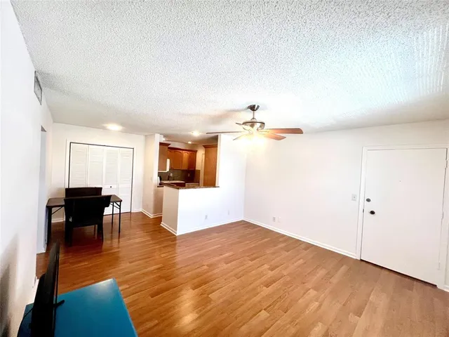 a view of kitchen and empty room with wooden floor