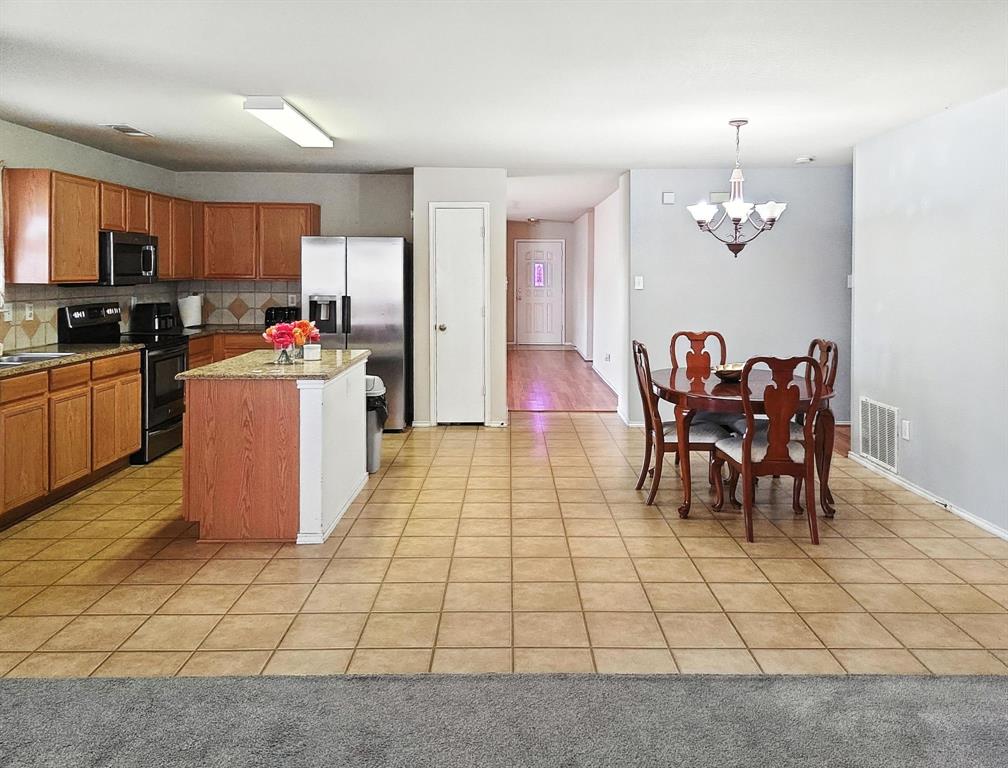 1330 White Tail Ridge Cedar Hill, TX 75104 - Photo 3 of 17 a kitchen with stainless steel appliances kitchen island granite countertop dining table chair and a refrigerator