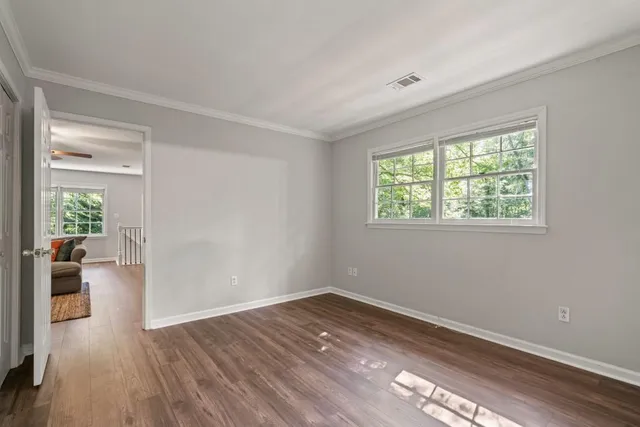 a view of empty room with wooden floor and fan