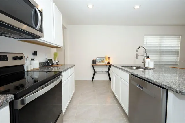a kitchen with stainless steel appliances granite countertop a sink refrigerator and cabinets