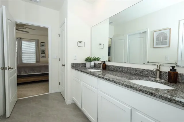 a bathroom with a granite countertop sink a mirror and shower