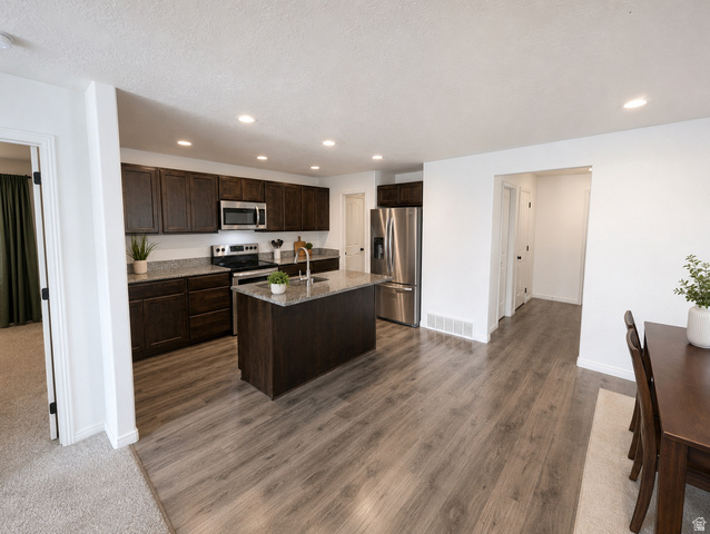 1687 South Windemere Road Santaquin, UT 84655 - Photo 8 of 27 Kitchen featuring dark wood cabinetry, stainless steel appliances, a center island with a sink, stone countertops, and wood-finish flooring