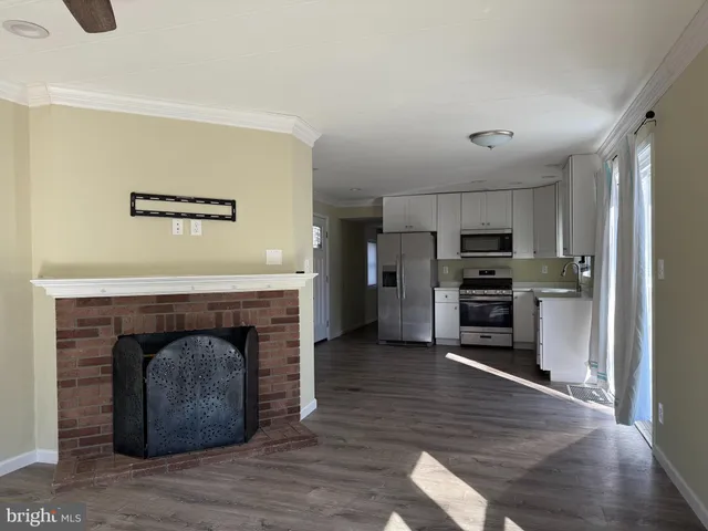 a living room with stainless steel appliances furniture a fireplace and wooden floor
