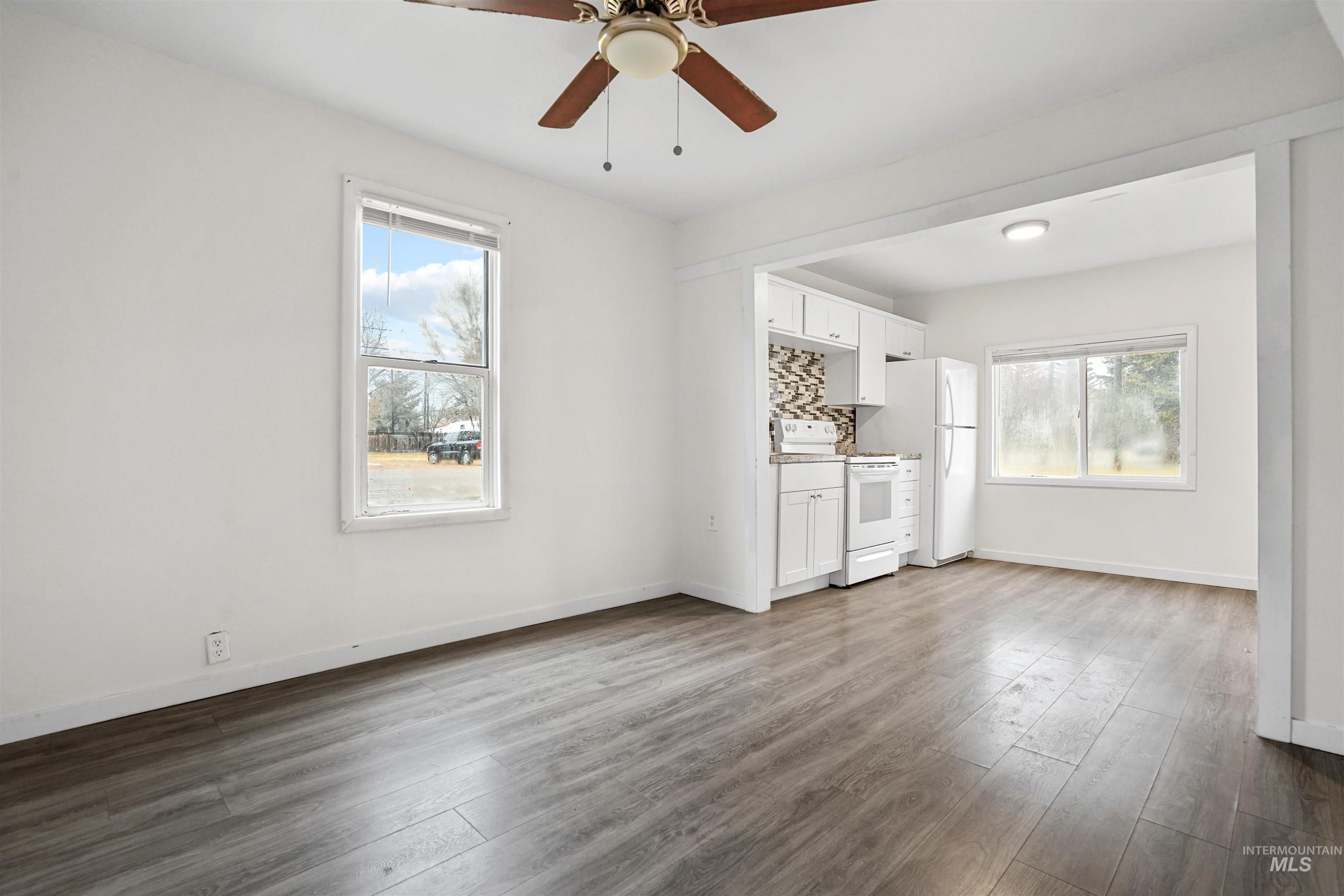 324 Linden Street Rupert, ID 83350 - Photo 3 of 13 Unfurnished living room with dark wood finished floors, healthy amount of natural light, and a ceiling fan