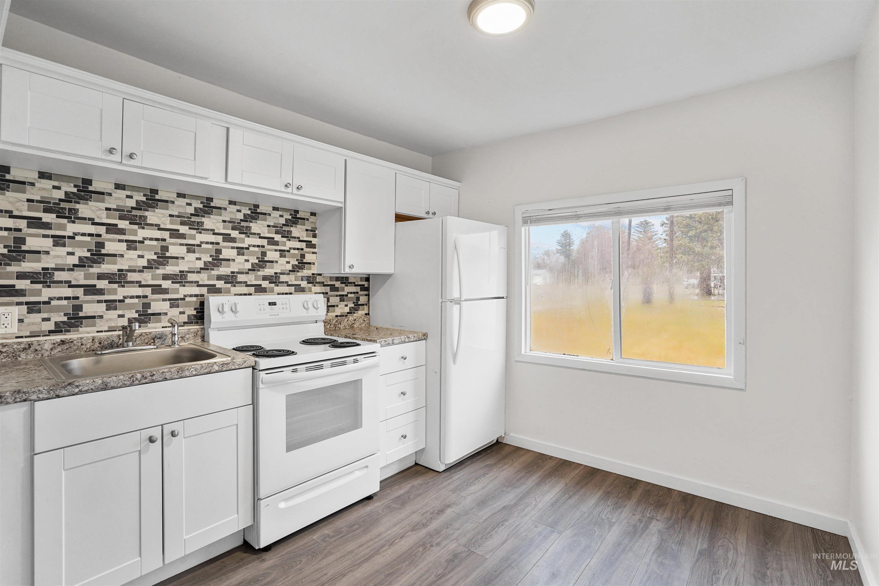 324 Linden Street Rupert, ID 83350 - Photo 4 of 13 Kitchen featuring white appliances, white cabinets, light wood finished floors, and tasteful backsplash