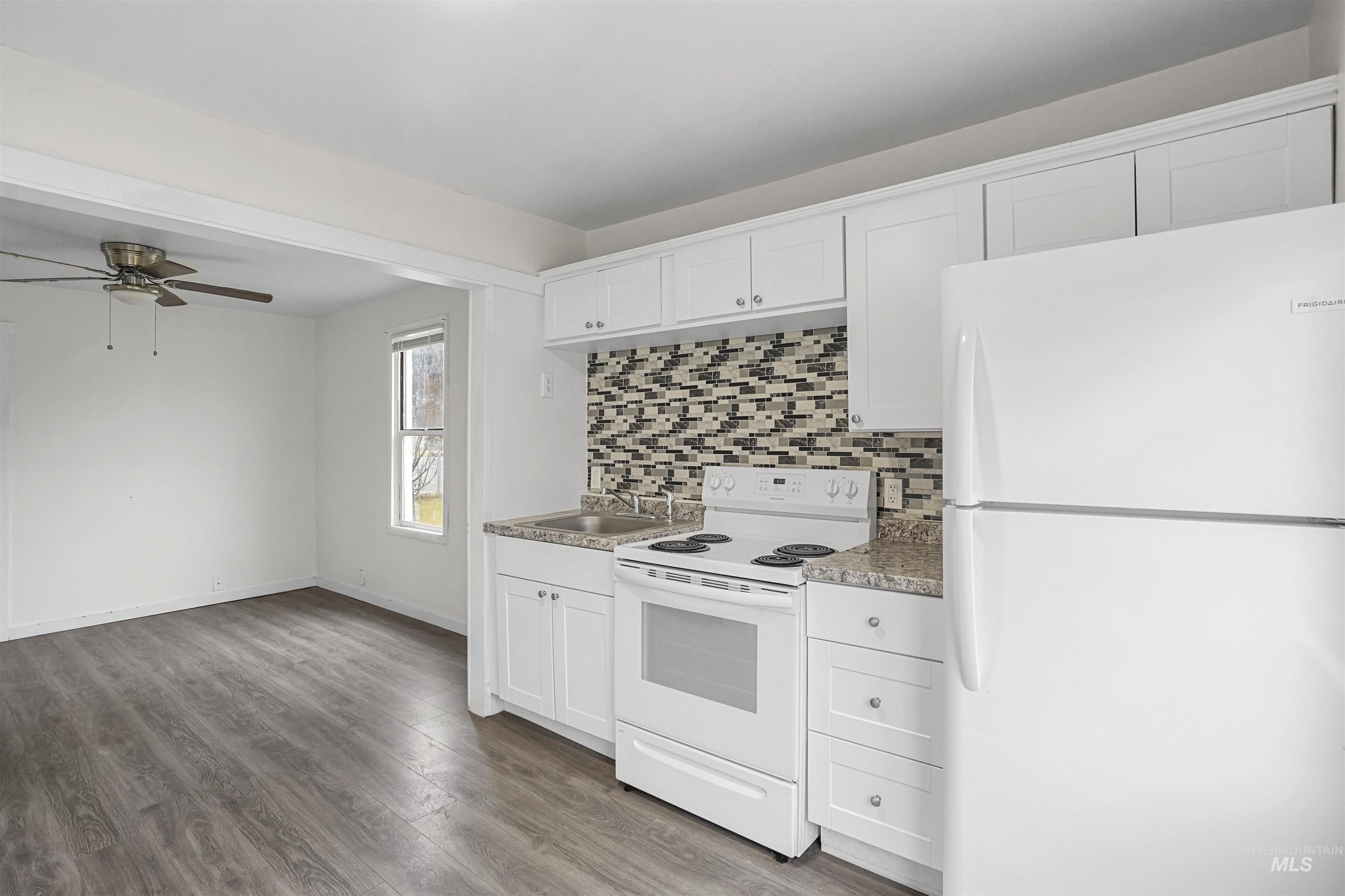 324 Linden Street Rupert, ID 83350 - Photo 5 of 13 Kitchen with white appliances, white cabinets, backsplash, light wood-style flooring, and light countertops