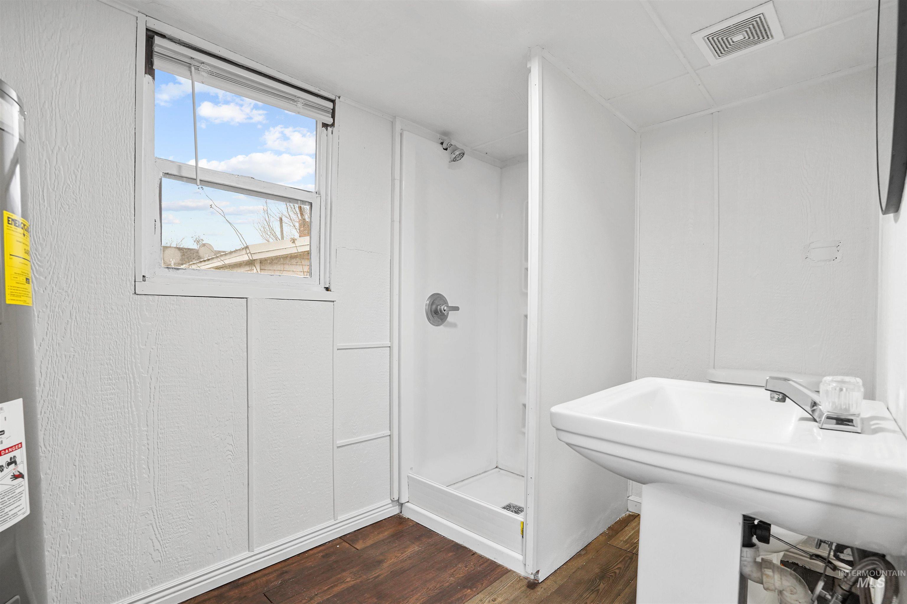 324 Linden Street Rupert, ID 83350 - Photo 8 of 13 Bathroom with a stall shower, dark wood finished floors, and water heater