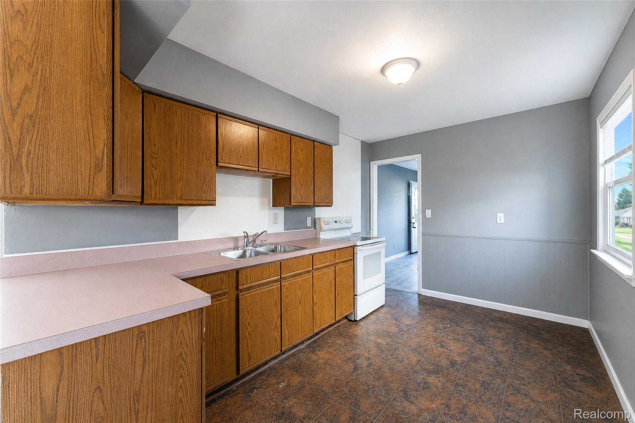 26137 Superior Road Taylor, MI 48180 - Photo 16 of 34 Well-lit kitchen featuring wood-finish cabinetry, a double basin stainless steel sink, and a white electric range
