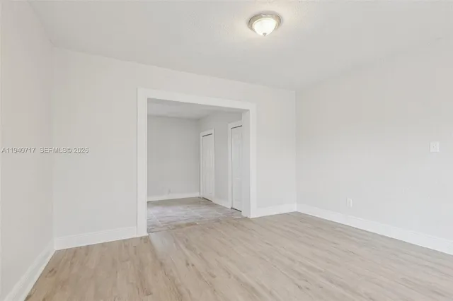 a view of an empty room with wooden floor and closet