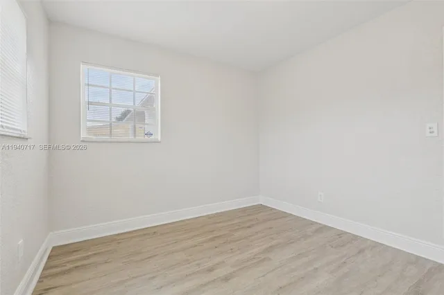 an empty room with wooden floor chandelier fan and windows