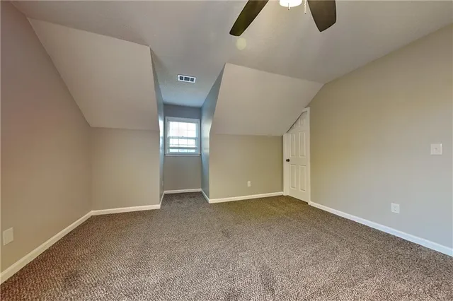 an empty room with chandelier fan and windows