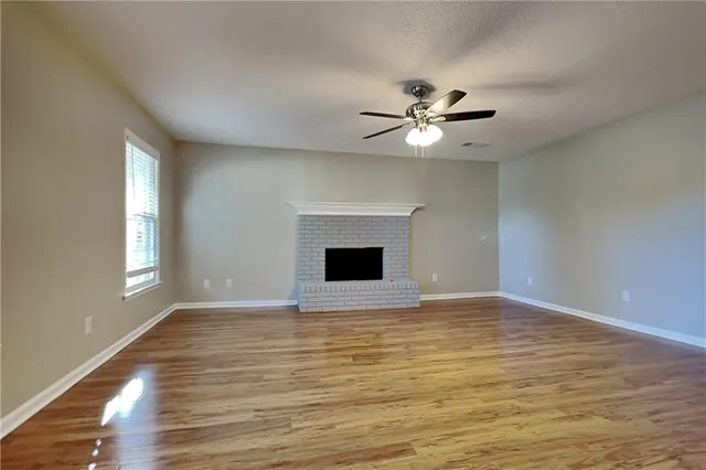 a view of an empty room with window and chandelier fan
