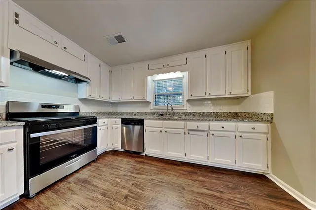 a kitchen with granite countertop wooden cabinets stainless steel appliances and a counter space