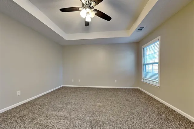 an empty room with windows and chandelier fan