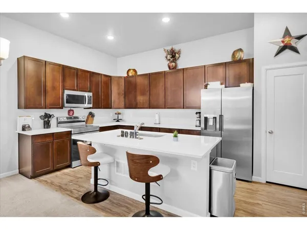 a kitchen with stainless steel appliances granite countertop a sink a stove a refrigerator cabinets and a dining table
