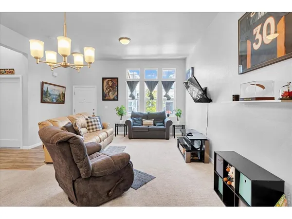 a living room with furniture a chandelier and a flat screen tv