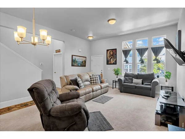 a living room with furniture a chandelier and a large mirror