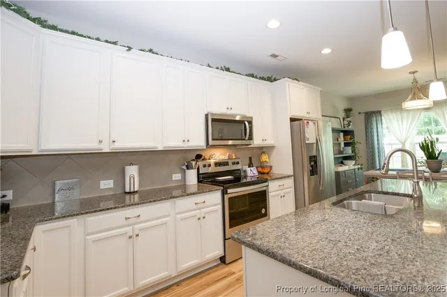 a kitchen with kitchen island granite countertop a sink stainless steel appliances and cabinets