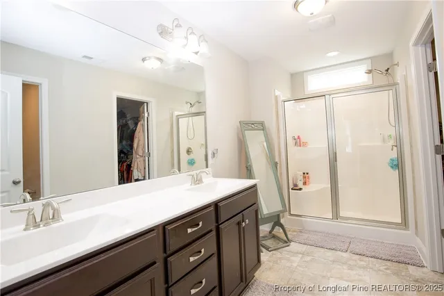 a spacious bathroom with a double vanity sink a mirror and a shower