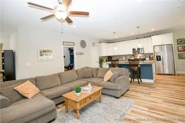 a view of a living room kitchen with stainless steel appliances granite countertop a couch and a chandelier