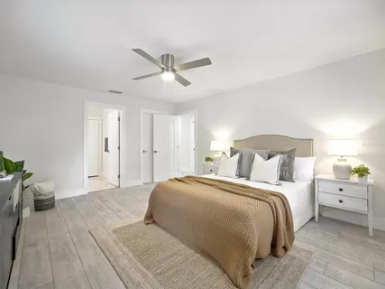 an empty room with wooden floor fan and windows