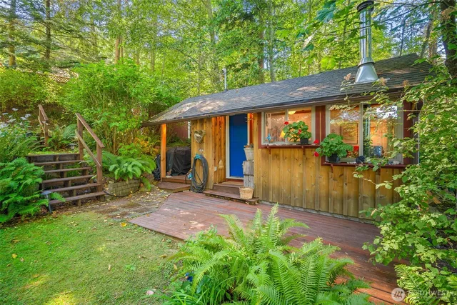 a backyard of a house with table and chairs floor to ceiling window and wooden fence